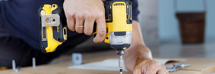 Person verschraubt Holzbretter mit Akkuschrauber